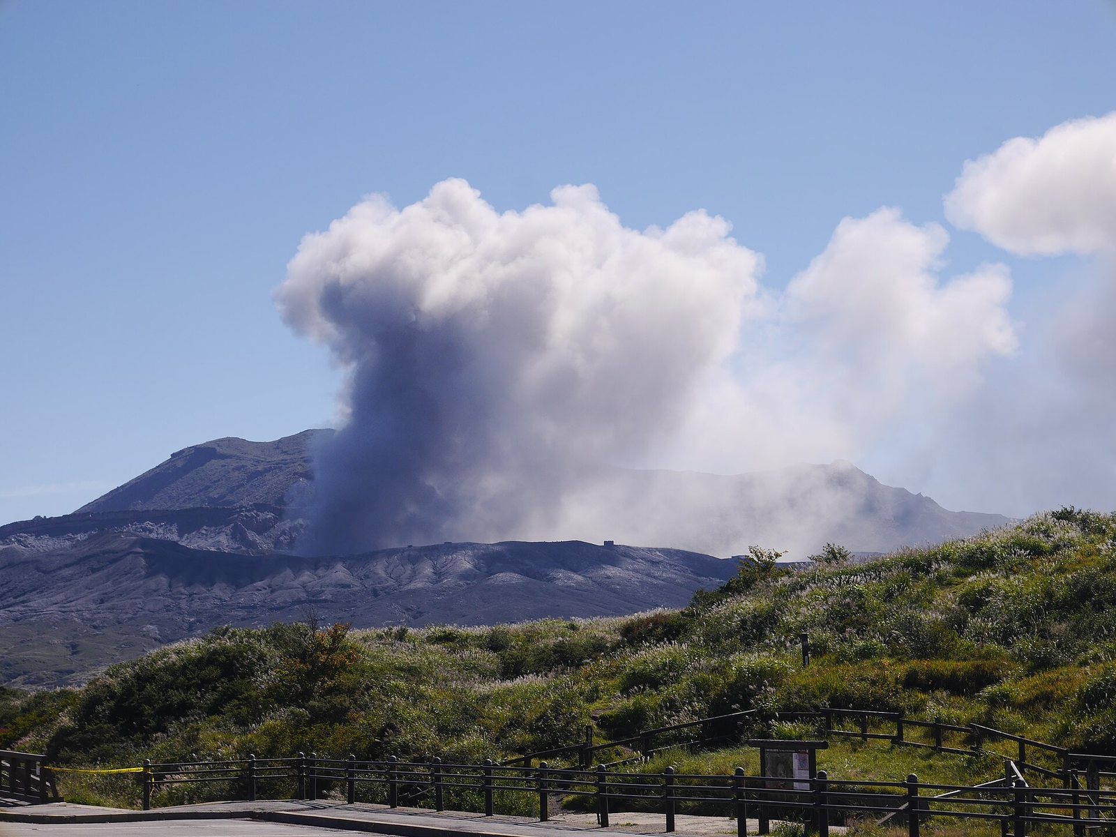 由草千里草原望向阿蘇中岳，火山口一帶冒着白煙。